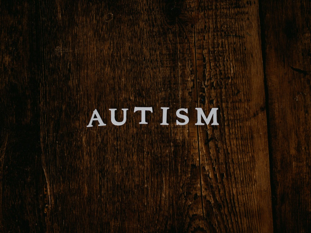 A wooden plank with the word Autism superimposed on it in white letters.