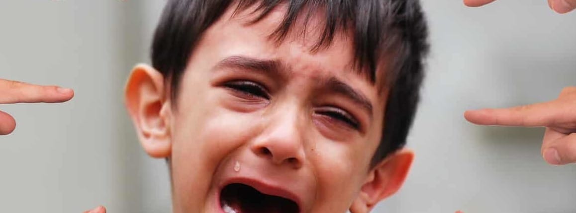 Crying boy with several kids pointing at him.