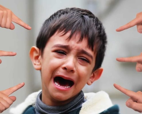 Crying boy with several kids pointing at him.