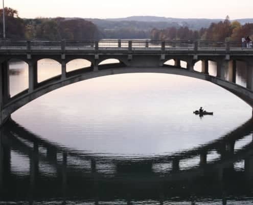 Bridge with old man fishing under it in a boat