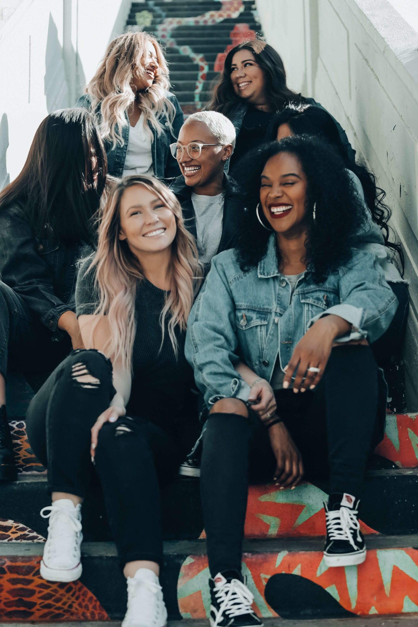A group of six laughing college-age women sitting in a stairwell.