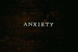 A wood backdrop has the word Anxiety written on it.
