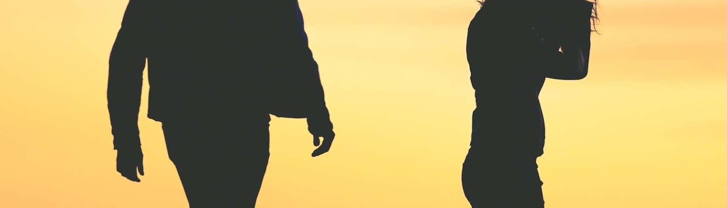 A couple has just broken up. A silhouette of a man and woman, with the woman crying at sunset