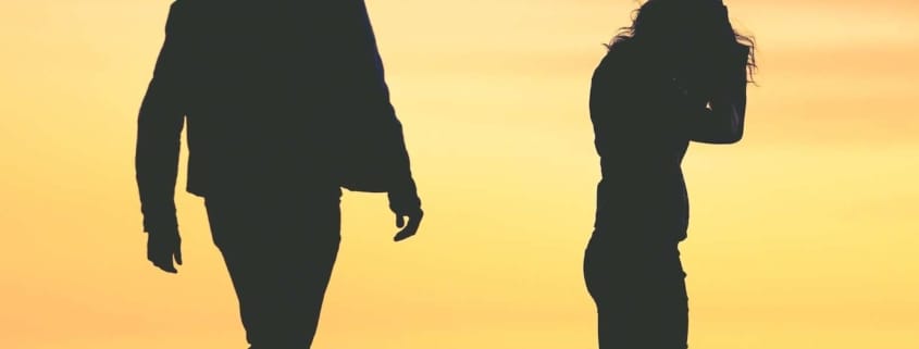 A couple has just broken up. A silhouette of a man and woman, with the woman crying at sunset