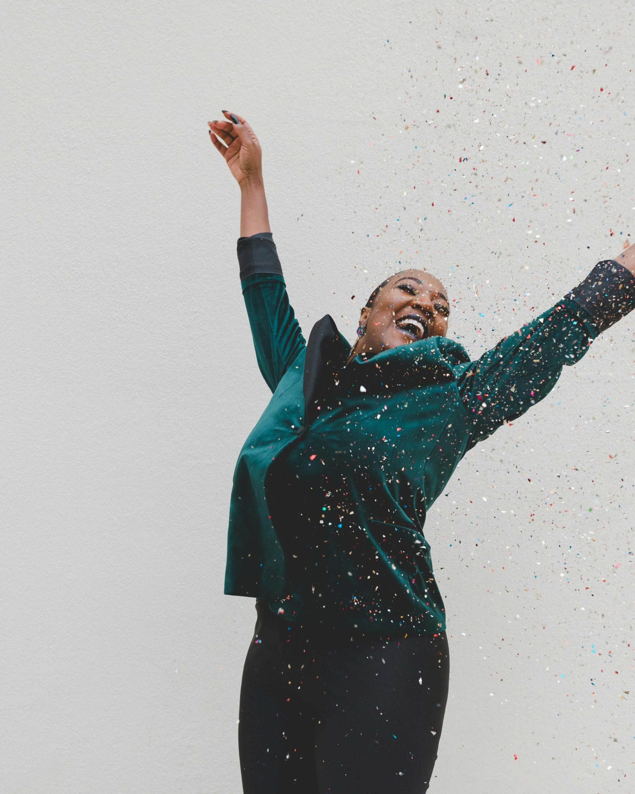 Woman jumping with joy and throwing confetti in celebration of reinventing herself.