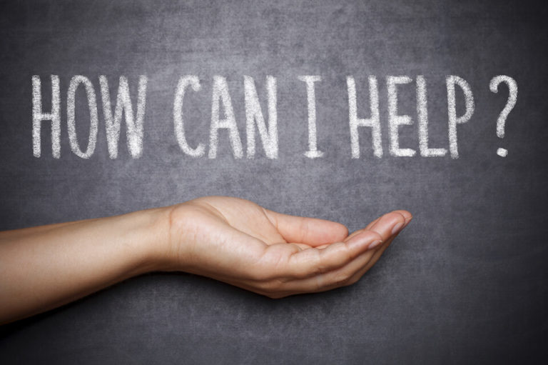 The words, "How can I help?" are written on a chalkboard with an open palm facing up under the words.