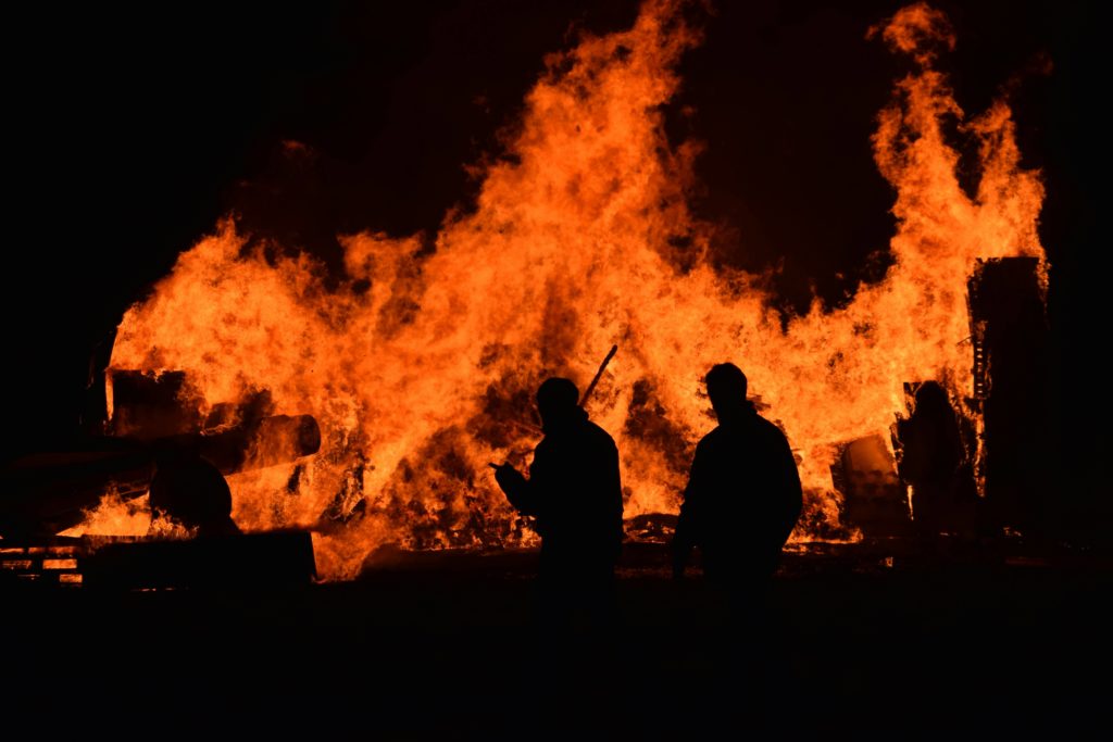People walking in front of a house fire.