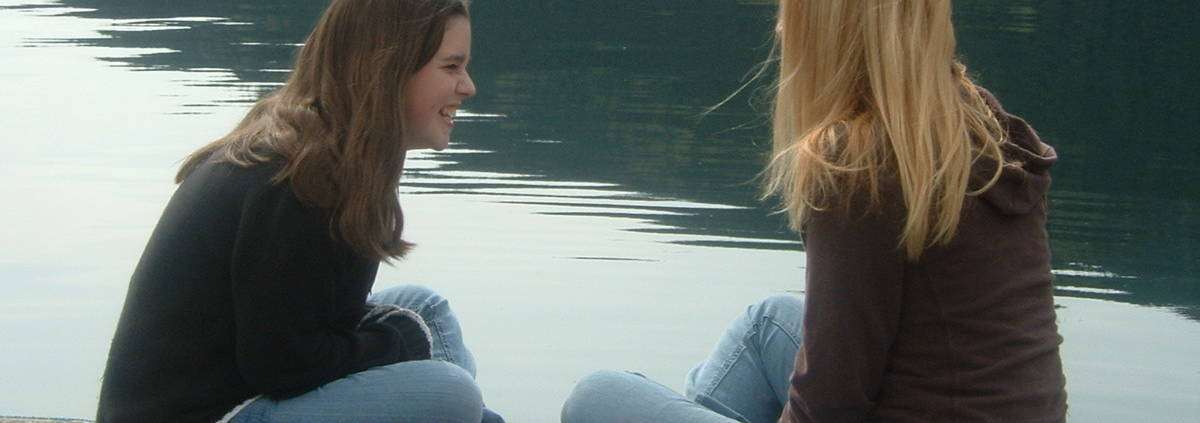 Two teen grils laughing on a pier. Peer counseling austin tx