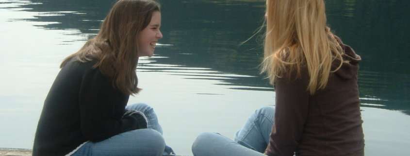 Two teen grils laughing on a pier. Peer counseling austin tx