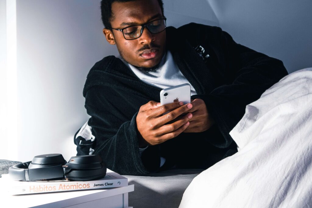 A young man lying awake in bed at night, looking at his phone