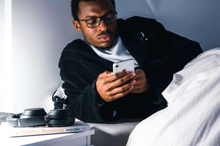 A young man lying awake in bed at night, looking at his phone