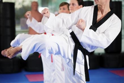 Several black belt students demonstrating a sidekick.