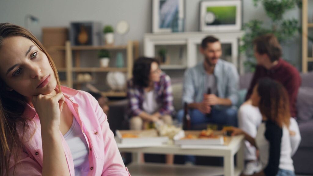 A woman sitting nervously away from a fun group.