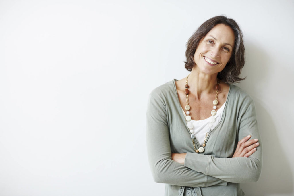 Self-aware woman smiling with folded arms.