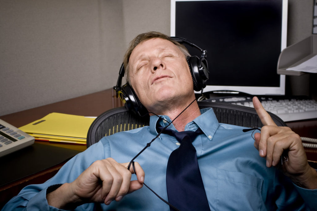 A man at his desk taking a break by listening to music in headphones