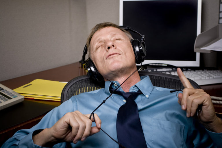 A man at his desk taking a break by listening to music in headphones