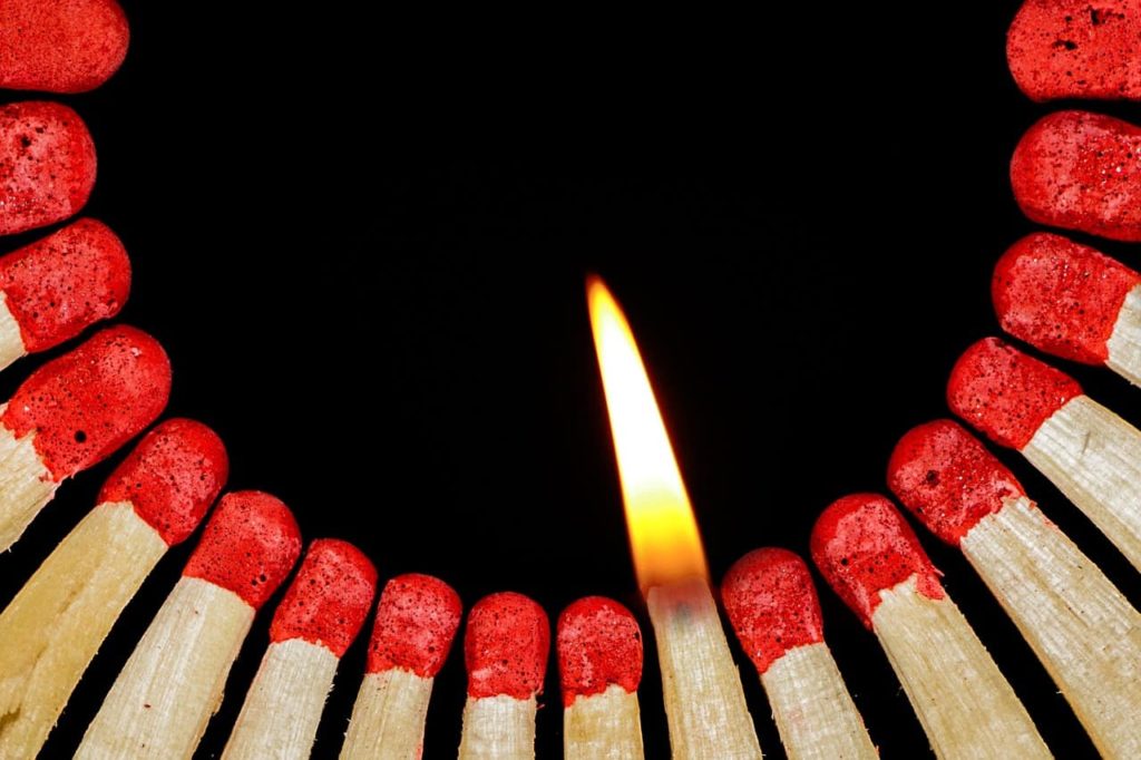 picture of a lit match close to a bunch of other unlit matches