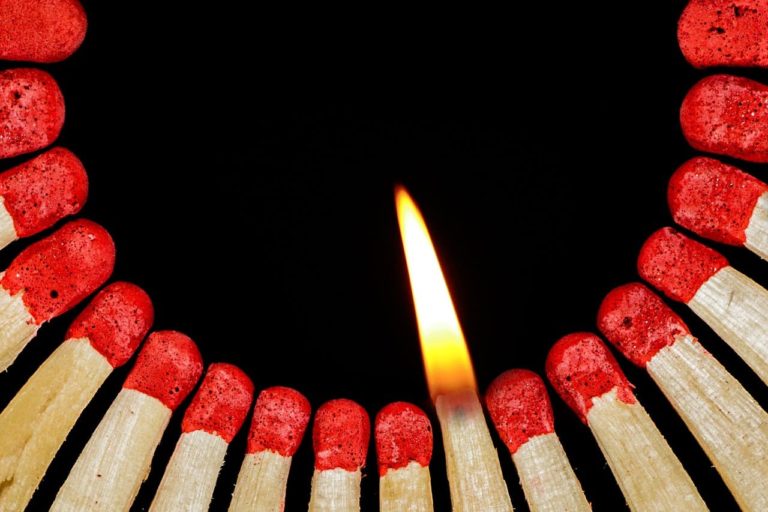 picture of a lit match close to a bunch of other unlit matches