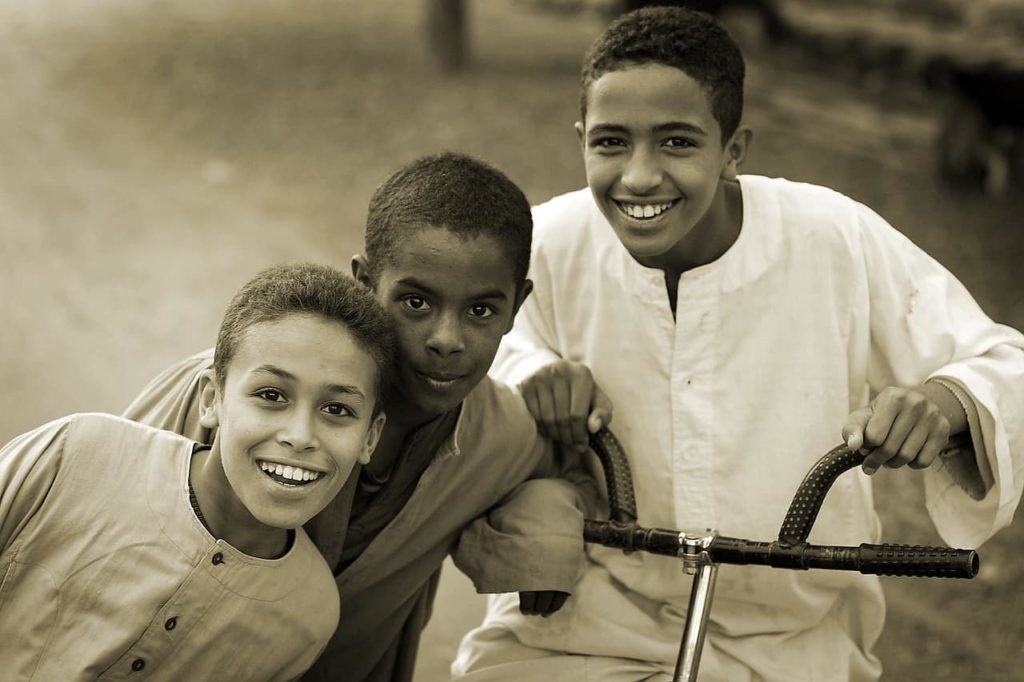 Three smiling teen boys in a row.