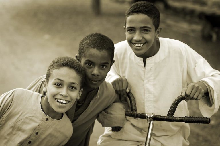 Three smiling teen boys in a row.