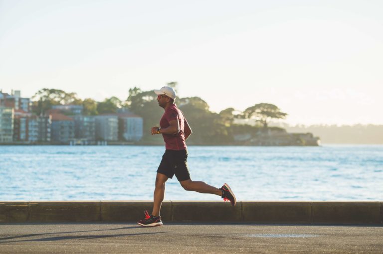 A man running on a path beside a lake.